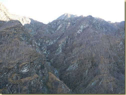 il percorso verso l'Alpe Taccarello sale sulla dorsale a destra, in alto la parete rocciosa con il "triangolo" 